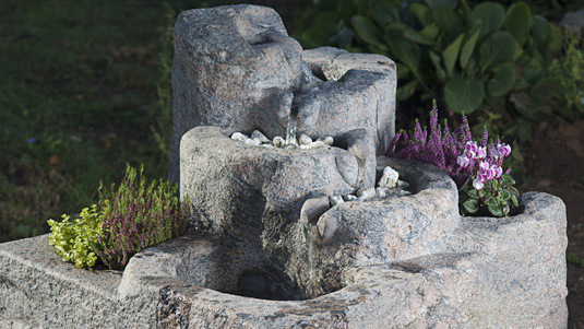 Ein bepflanzter Natursteinbrunnen mit Bachlauf ist im Garten oder auf der Terrasse ein Highlight.